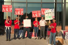 Group of people holding aaup signs in protest outside a university building